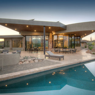 Immagine di un grande patio o portico design dietro casa con un focolare, piastrelle e un tetto a sbalzo