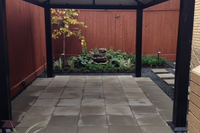 Diseño de patio moderno pequeño en patio trasero con fuente, adoquines de hormigón y cenador