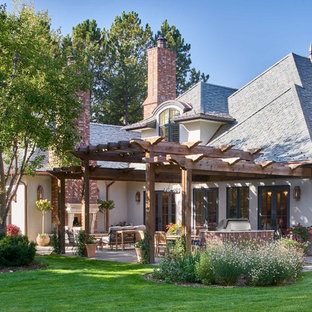 Immagine di un grande patio o portico classico dietro casa con un caminetto, pavimentazioni in pietra naturale e una pergola