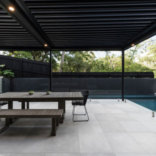 Foto di un patio o portico contemporaneo nel cortile laterale con piastrelle e una pergola