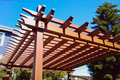 Cette photo montre une terrasse avec des plantes en pots arrière chic de taille moyenne avec une pergola.