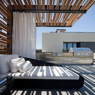 Example of a huge minimalist backyard concrete paver patio kitchen design in Las Vegas with a pergola