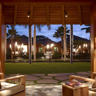 Idee per un patio o portico tropicale con pavimentazioni in pietra naturale e un tetto a sbalzo