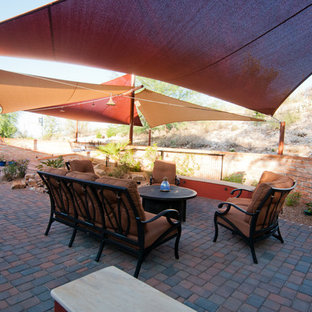 Immagine di un patio o portico stile americano di medie dimensioni e dietro casa con pavimentazioni in mattoni e un parasole