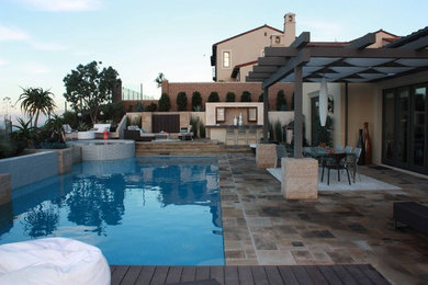 Exemple d'une grande terrasse arrière tendance avec une cuisine d'été, des pavés en pierre naturelle et une pergola.