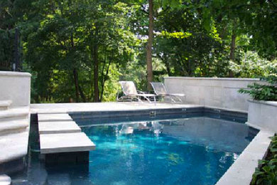 Ejemplo de piscina con fuente de tamaño medio en patio trasero con adoquines de piedra natural