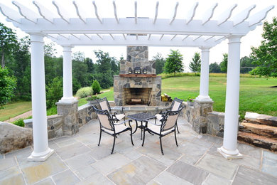 Immagine di un patio o portico chic con pavimentazioni in pietra naturale, un focolare e una pergola