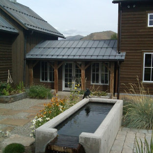 Idee per un ampio patio o portico country in cortile con fontane, pavimentazioni in pietra naturale e un tetto a sbalzo