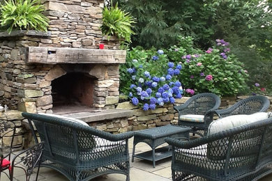 This is an example of a large traditional back patio in New York with a fire feature, stamped concrete and no cover.