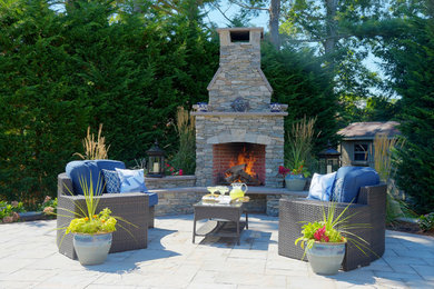 Example of a mid-sized trendy backyard stone patio design in New York with a fire pit and no cover