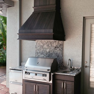 Ispirazione per un grande patio o portico tropicale dietro casa con pavimentazioni in cemento e un tetto a sbalzo