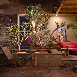 Immagine di un patio o portico etnico con lastre di cemento e una pergola
