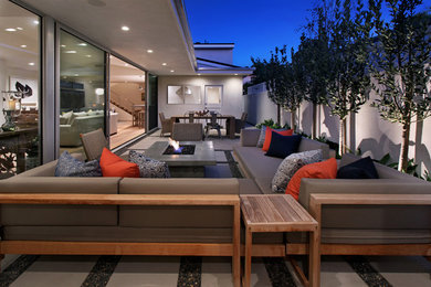 Example of a large trendy backyard concrete paver patio design in Orange County with a fire pit and no cover