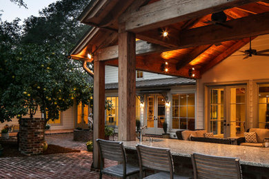 Example of a large classic backyard brick patio kitchen design in New Orleans with a roof extension