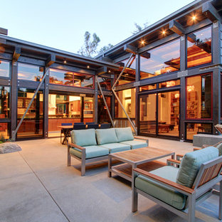 Immagine di un grande patio o portico industriale dietro casa con un focolare, lastre di cemento e nessuna copertura