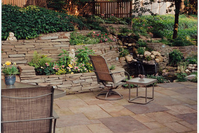 Ejemplo de patio clásico en patio trasero con fuente y adoquines de piedra natural
