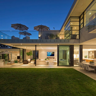 Idee per un ampio patio o portico minimal dietro casa con un focolare, piastrelle e un tetto a sbalzo