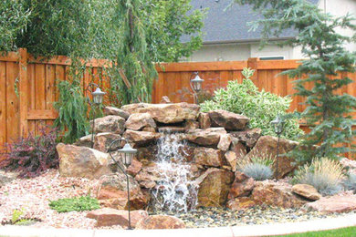 Foto de patio de estilo zen de tamaño medio sin cubierta en patio trasero con fuente y gravilla
