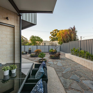 Immagine di un patio o portico bohémian di medie dimensioni e dietro casa con un giardino in vaso, lastre di cemento e un parasole