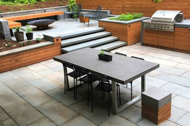 Photo of a modern back patio in Philadelphia with an outdoor kitchen, natural stone paving and no cover.