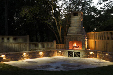 Cette image montre une terrasse arrière traditionnelle de taille moyenne avec un foyer extérieur et des pavés en pierre naturelle.