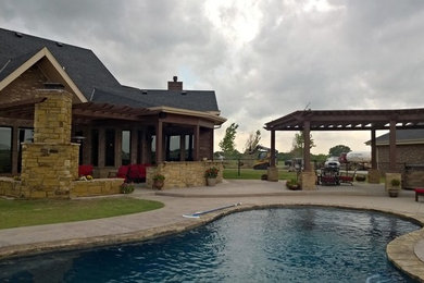Inspiration for a large rustic backyard stamped concrete patio kitchen remodel in Oklahoma City with a pergola
