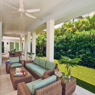 Idee per un patio o portico tropicale dietro casa con pavimentazioni in cemento e un tetto a sbalzo