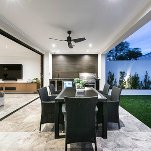 Immagine di un patio o portico design dietro casa con piastrelle e un tetto a sbalzo