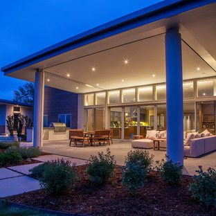 Foto di un grande patio o portico minimal dietro casa con un tetto a sbalzo e pavimentazioni in cemento