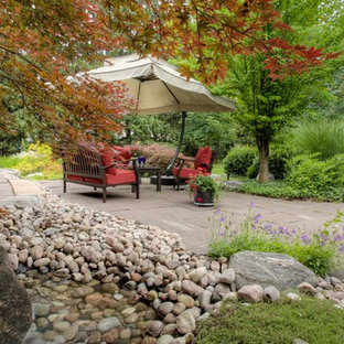 Foto di un ampio patio o portico eclettico dietro casa con fontane e pavimentazioni in cemento