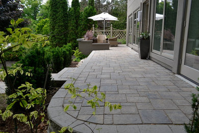 Example of a large mountain style front yard concrete paver patio design in Toronto