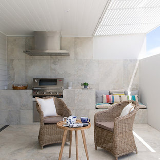 Foto di un piccolo patio o portico moderno in cortile con piastrelle e un tetto a sbalzo