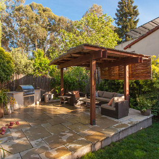 Esempio di un piccolo patio o portico eclettico dietro casa con pavimentazioni in pietra naturale e una pergola