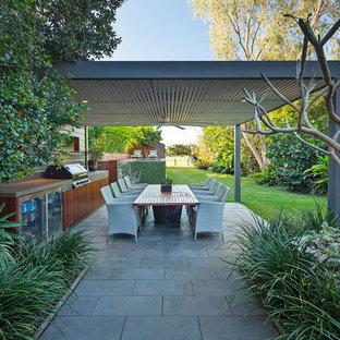 Tropical backyard patio in Brisbane with an outdoor kitchen, concrete pavers and a pergola.