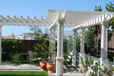 Imagen de patio clásico de tamaño medio en patio trasero con jardín de macetas, adoquines de hormigón y pérgola