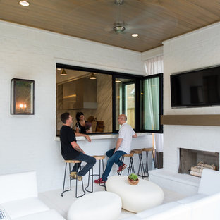 Foto di un grande patio o portico chic dietro casa con un focolare, piastrelle e un tetto a sbalzo