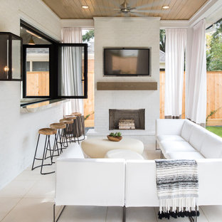 Immagine di un patio o portico contemporaneo di medie dimensioni e dietro casa con piastrelle, un tetto a sbalzo e un caminetto