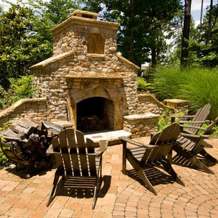 Immagine di un patio o portico chic con pavimentazioni in mattoni e un focolare