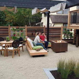 Foto di un piccolo patio o portico moderno dietro casa con un focolare, graniglia di granito e una pergola