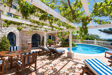 Ejemplo de casa de la piscina y piscina alargada mediterránea de tamaño medio tipo riñón en patio con suelo de baldosas