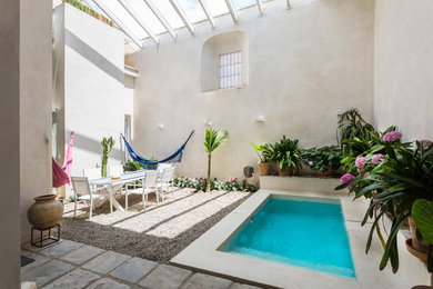 Ejemplo de piscina mediterránea rectangular en patio con gravilla