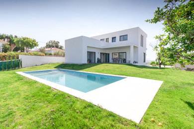Ejemplo de piscina alargada moderna de tamaño medio rectangular en patio trasero con suelo de baldosas
