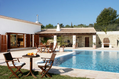 Imagen de piscina mediterránea grande rectangular en patio trasero con adoquines de piedra natural
