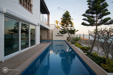 Imagen de piscina con fuente alargada moderna grande en forma de L en patio trasero con suelo de baldosas