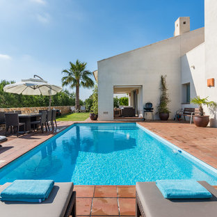 Diseño de piscina alargada, mediterránea, rectangular, en patio trasero, con suelo de baldosas