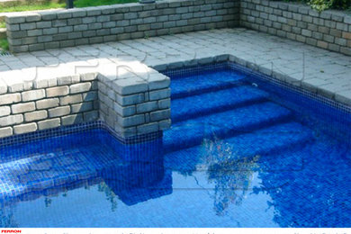Modelo de piscina tradicional de tamaño medio rectangular en patio trasero con adoquines de piedra natural