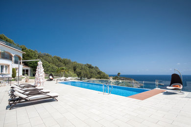 Ejemplo de piscina infinita mediterránea grande rectangular en patio trasero