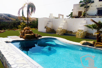 Imagen de piscinas y jacuzzis alargados tropicales grandes a medida en patio trasero con gravilla