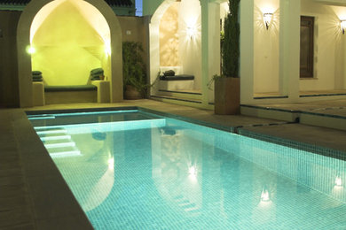 Imagen de piscina con fuente alargada de tamaño medio rectangular en patio con suelo de baldosas
