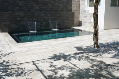 Diseño de piscina con fuente natural exótica rectangular en patio con suelo de baldosas